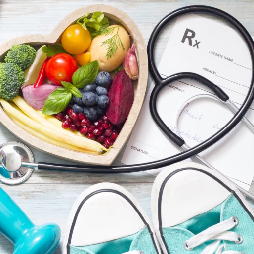 urządzenia do ćwiczeń, trampki niebieskie, stetoskop, misa drewniana w kształcie serca z warzywami i owocami